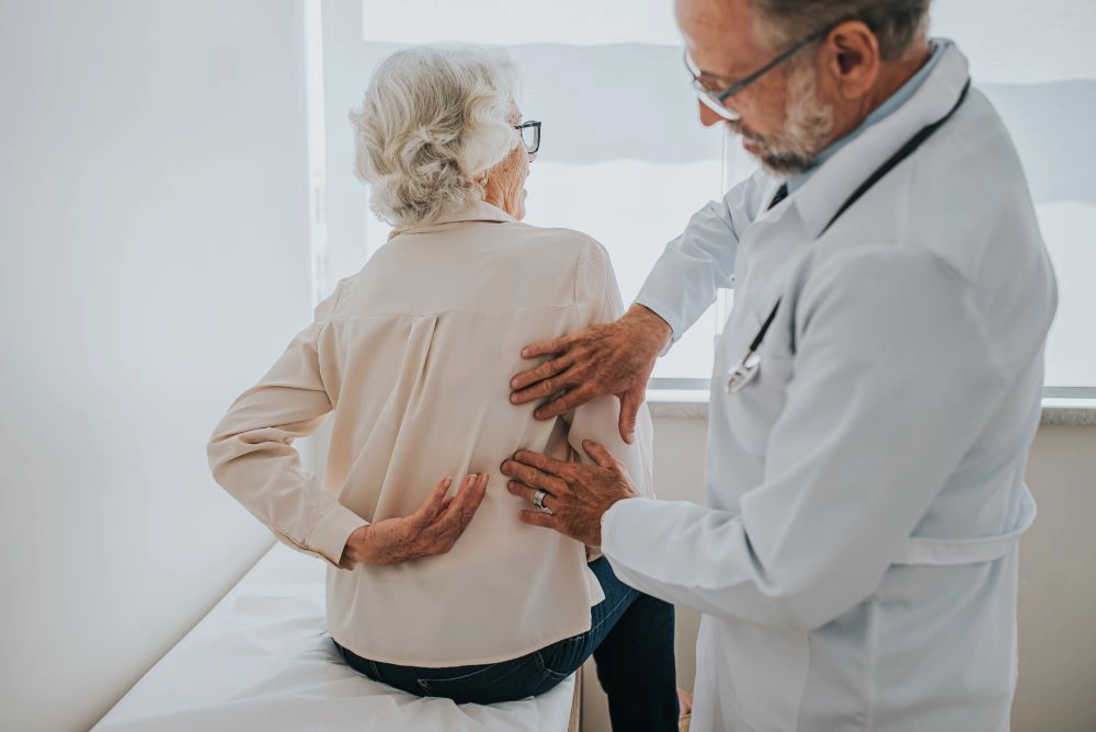 Provider examining elderly female patient's back
